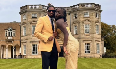 Elegantly dressed couple posing in front of mansion