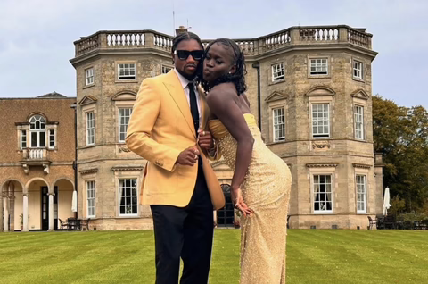 Elegantly dressed couple posing in front of mansion