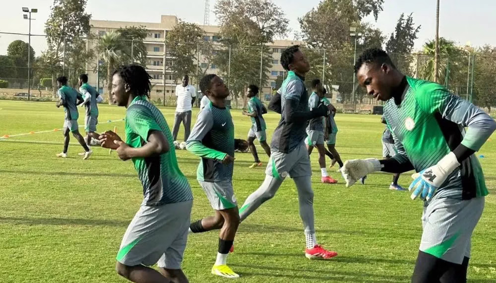 Soccer team training on field in green uniforms.