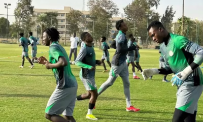 Soccer team training on field in green uniforms.
