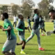 Soccer team training on field in green uniforms.